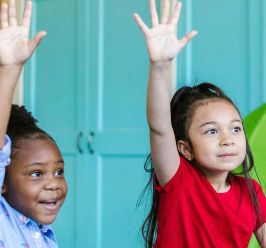 Two young children with their hands raised.